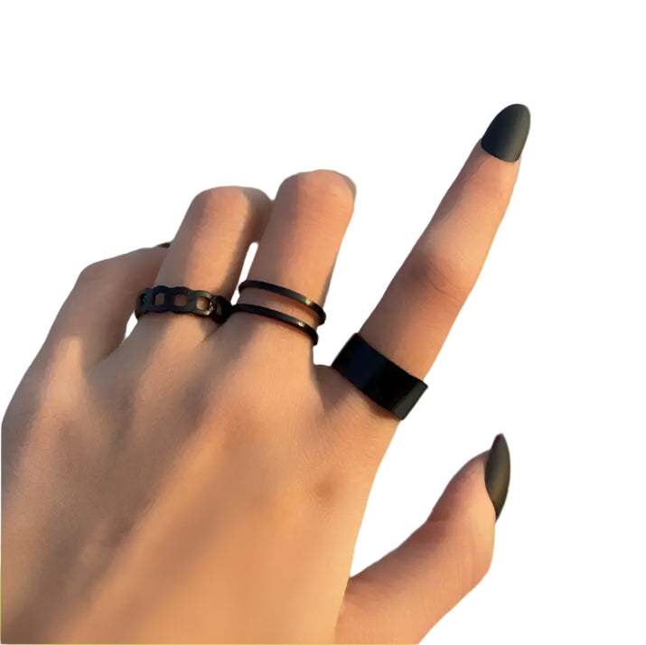Hand wearing multiple black rings on a neutral background