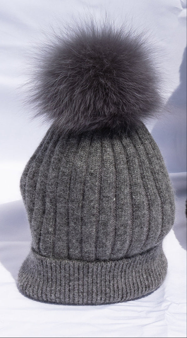 Gray knitted beanie with a large fur pom-pom on a white background