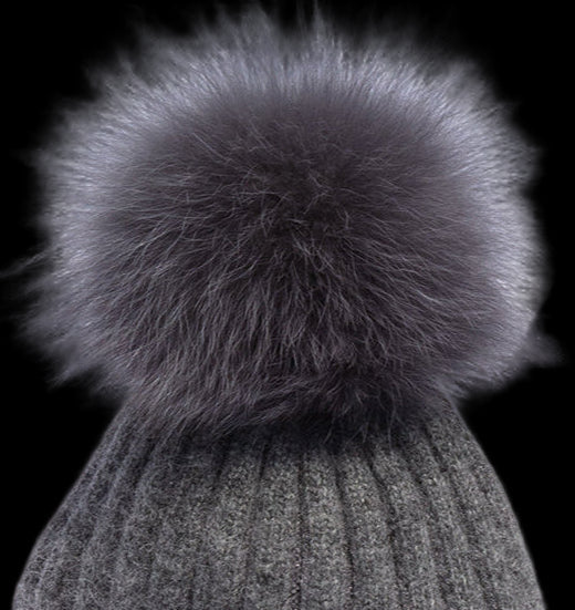 Gray knitted beanie with a large fur pom-pom on a white background