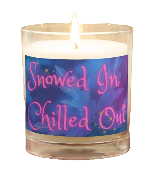 Candle with a label reading 'Snowed In Chilled Out' held by a person wearing a beige sweater.