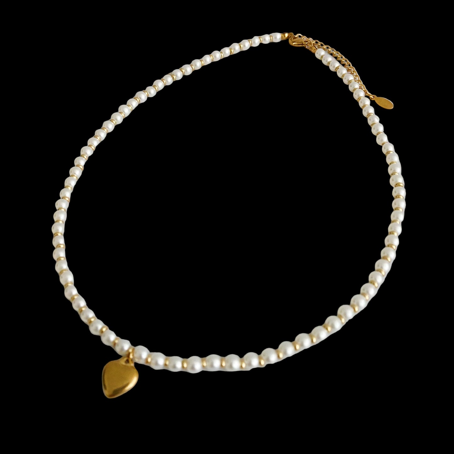 Pearl necklace with gold heart pendants on a light background