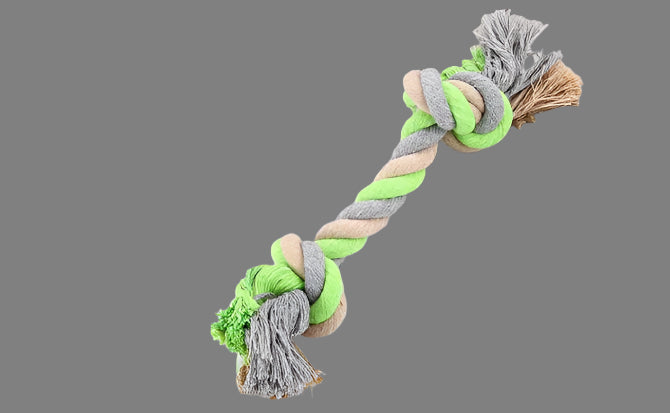 Green and gray braided pet toy on a white surface with a book in the background.
