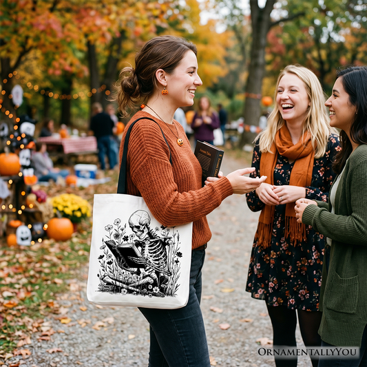 Three women laughing together in a park with autumn foliage, one holding a tote bag with a skeleton design.