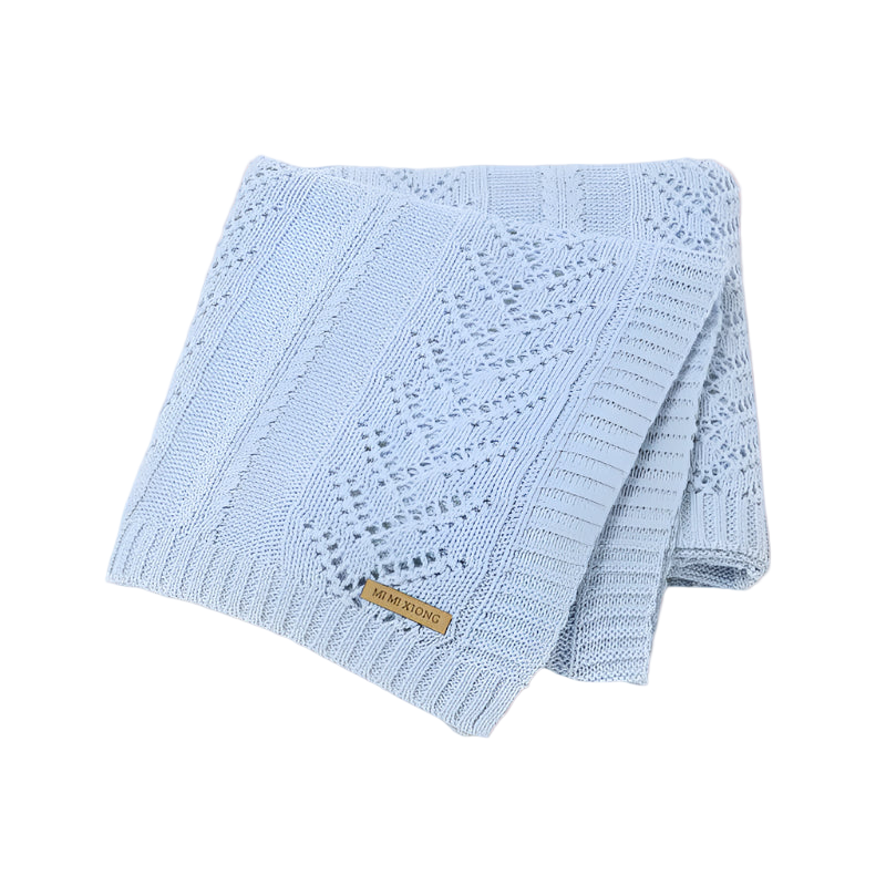 Light blue knitted blanket with a brand label on a white background