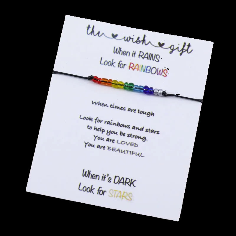 Rainbow beaded bracelet on a card with motivational text on a wooden surface