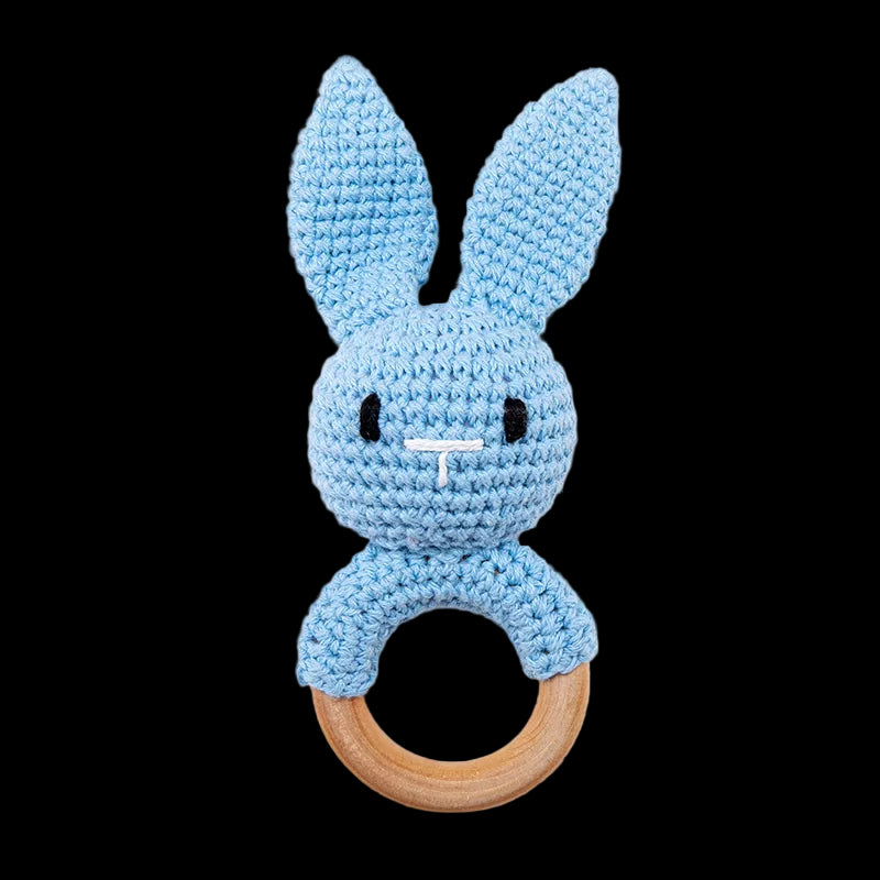 Blue crocheted bunny rattle with wooden ring on a white background