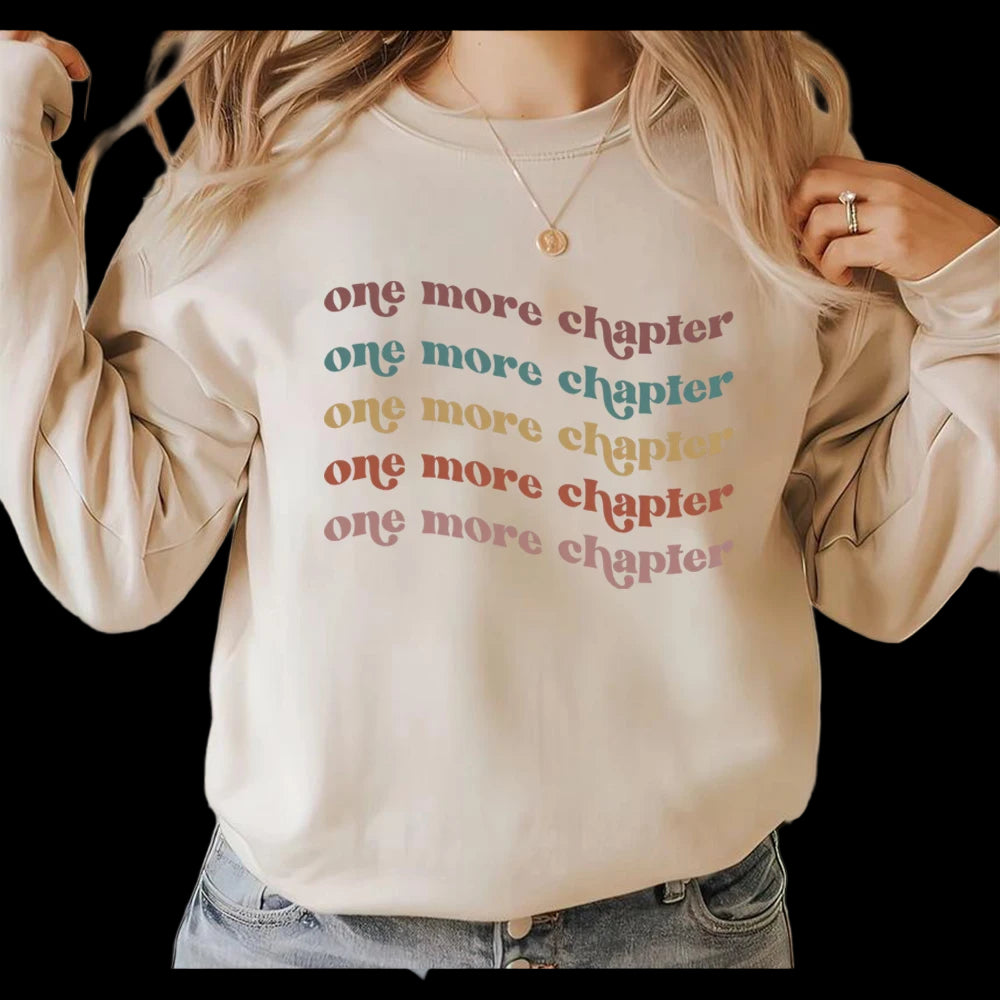 Beige sweatshirt with 'one more chapter' text in various colors, worn by a person.