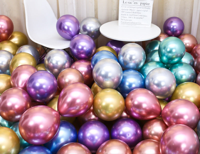 Colorful metallic balloons on a chair with a small plant and card in the background.