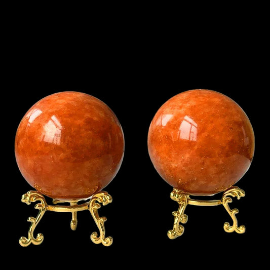 Two orange spheres on gold stands against a white background