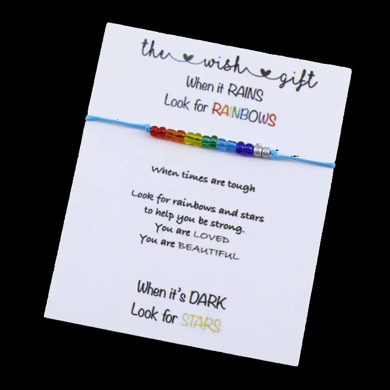 Rainbow beaded bracelet on a card with motivational text on a wooden surface