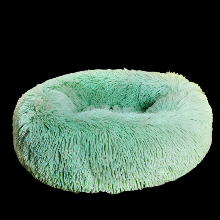 Mint green fluffy pet bed on a beige carpet with a yellow chair in the background
