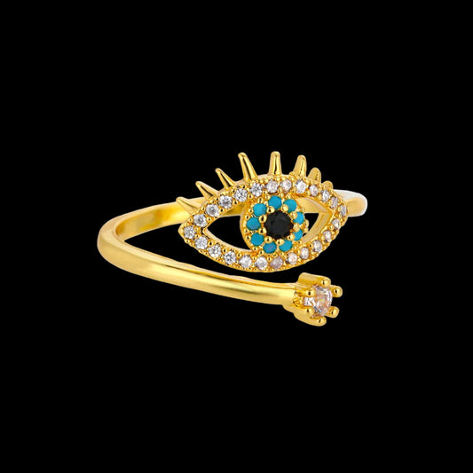 Gold ring with eye design and gemstones on a white background