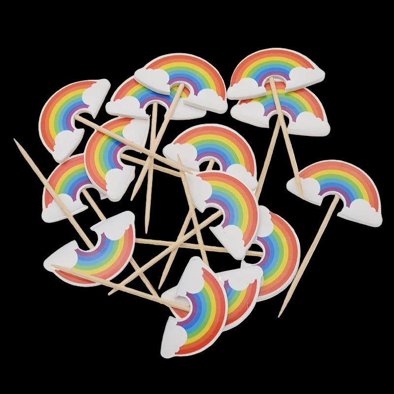 Rainbow and cloud-shaped cupcake toppers with wooden sticks on a white background.