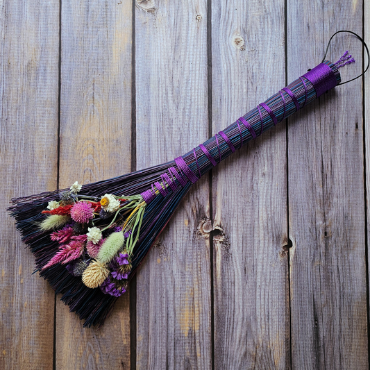 Decorative broom with flowers on a wooden surface