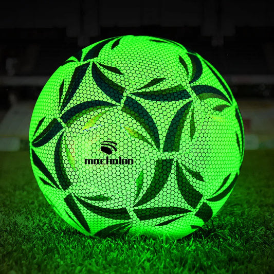 Green soccer ball with black patterns on grass at night