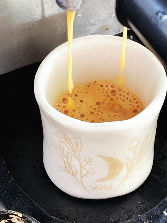 Coffee being poured into a white mug with a decorative design.