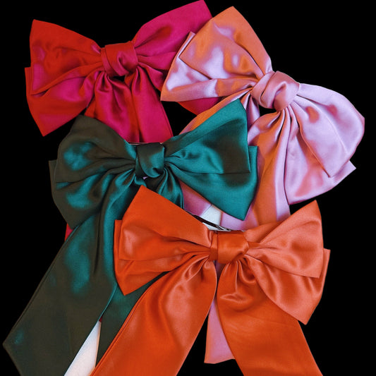 Five colorful satin bows in red, pink, green, and orange on a light background.