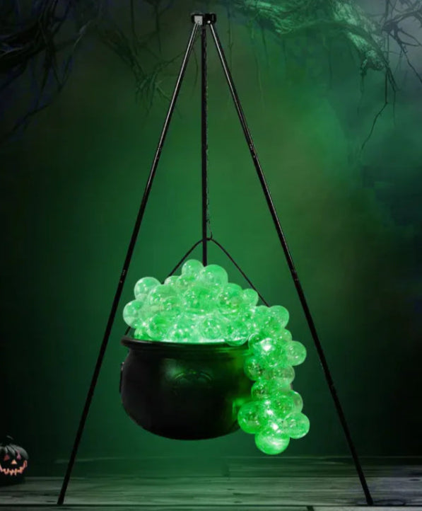 Hanging cauldron with glowing green bubbles against a dark background