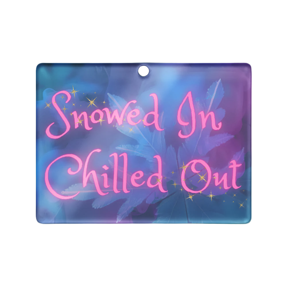 Decorative sign with 'Snowed In Chilled Out' text on a blue and pink gradient background