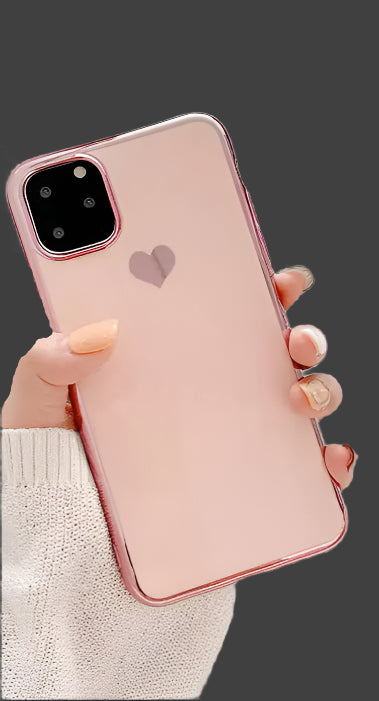 Person holding a pink phone with a heart design on a light surface
