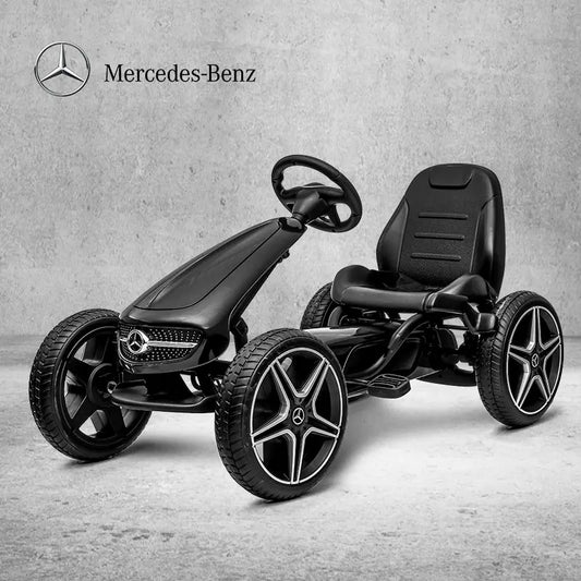 Black Mercedes-Benz pedal car on a gray concrete floor with the Mercedes-Benz logo above.