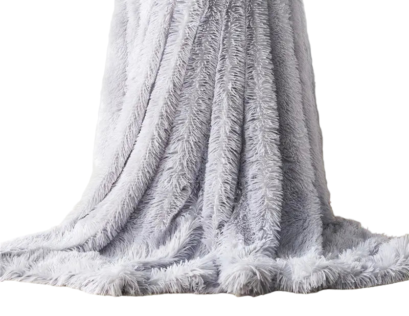 Fluffy gray blanket draped over a chair with a plant and magazine in the background.