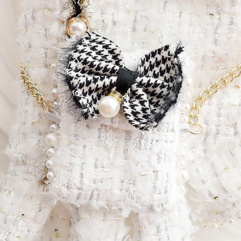 Black and white patterned hair bow with pearl accents on a textured white background