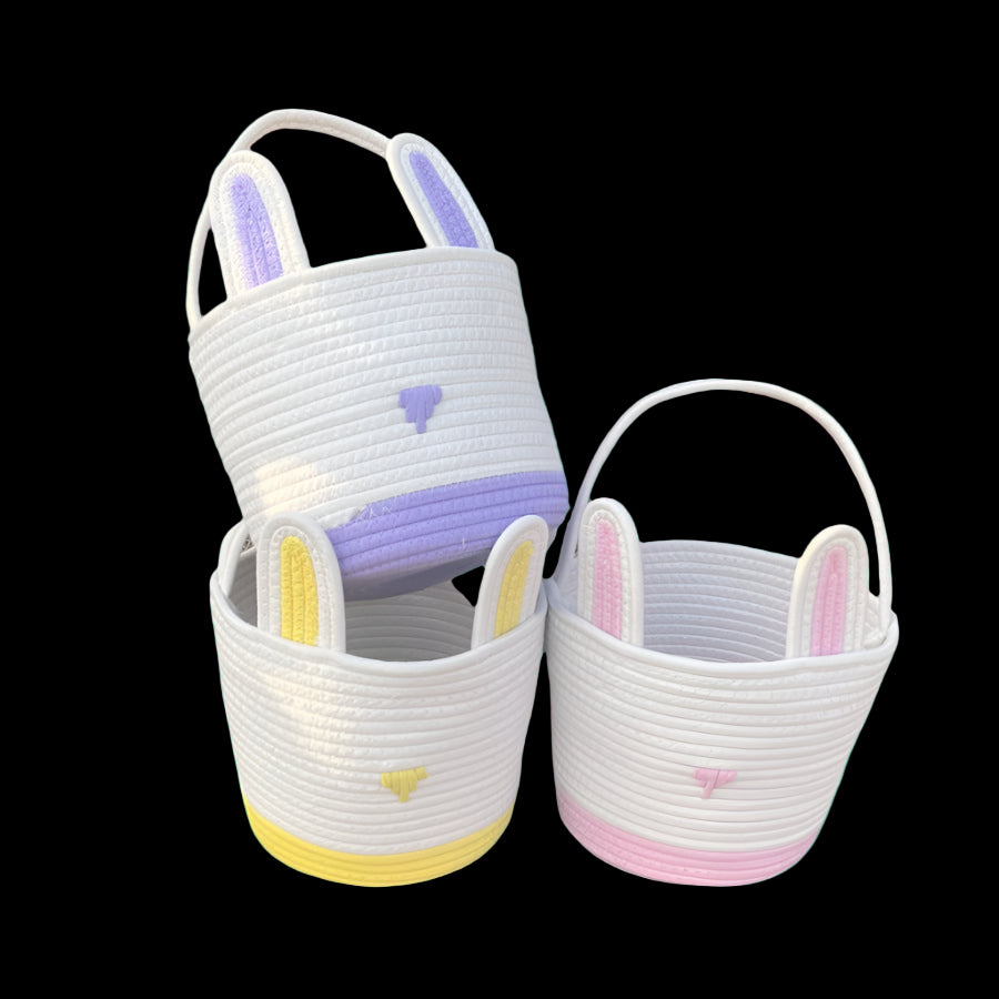 Three woven baskets with bunny ears on a stone surface outdoors.