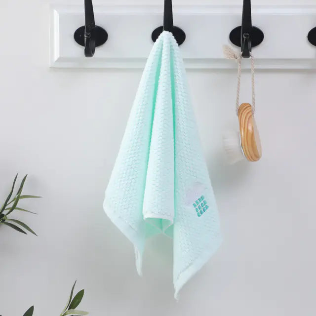Light blue towel hanging on a hook with a white background