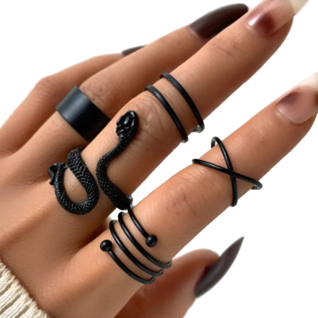 Close-up of a hand wearing multiple black rings on a light background