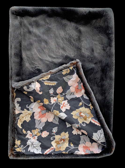 Floral-patterned blanket with gray border on a dark background
