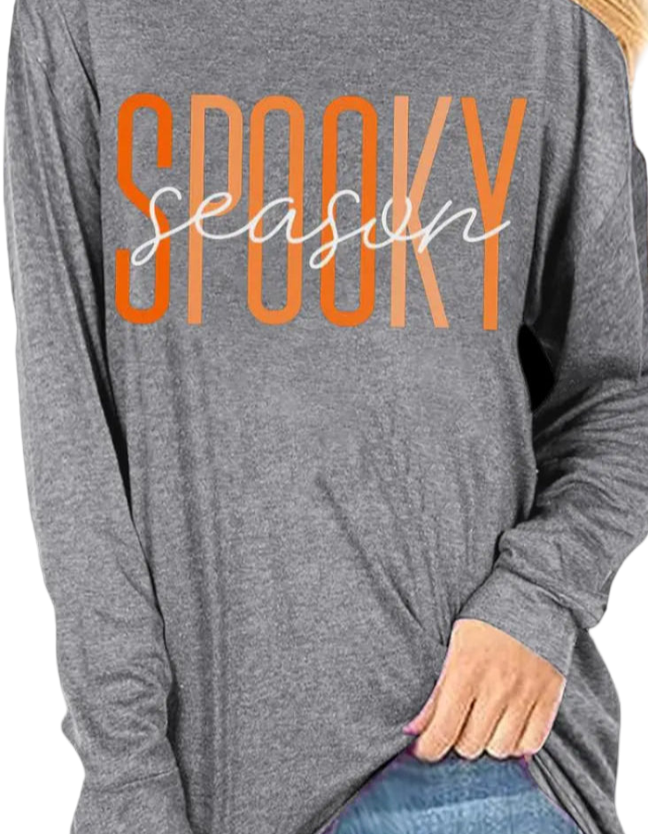 Woman wearing a gray long-sleeve shirt with 'Spooky season' text in orange and white.