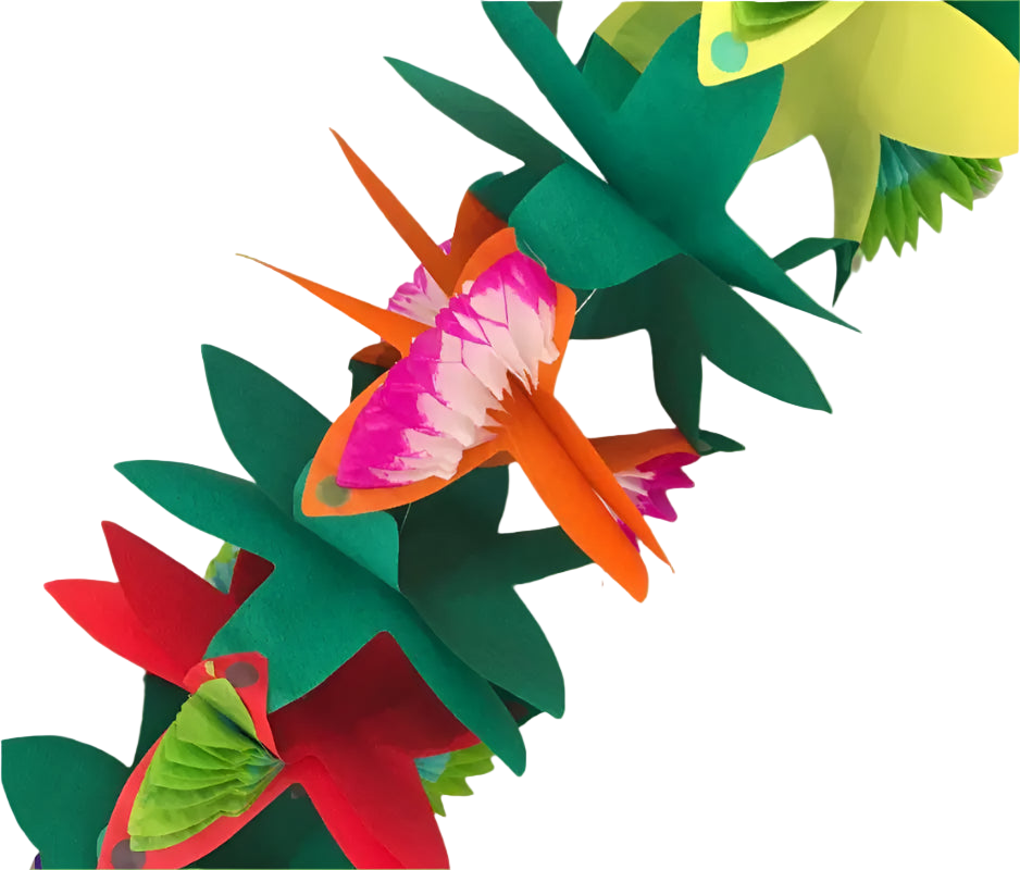 Colorful paper flowers on a white surface with green leaves in the background