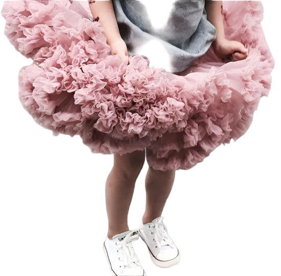 Child wearing a fluffy pink skirt and white sneakers on a gray surface