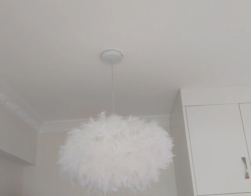 White feathered pendant light fixture hanging from a ceiling in a minimalistic room.