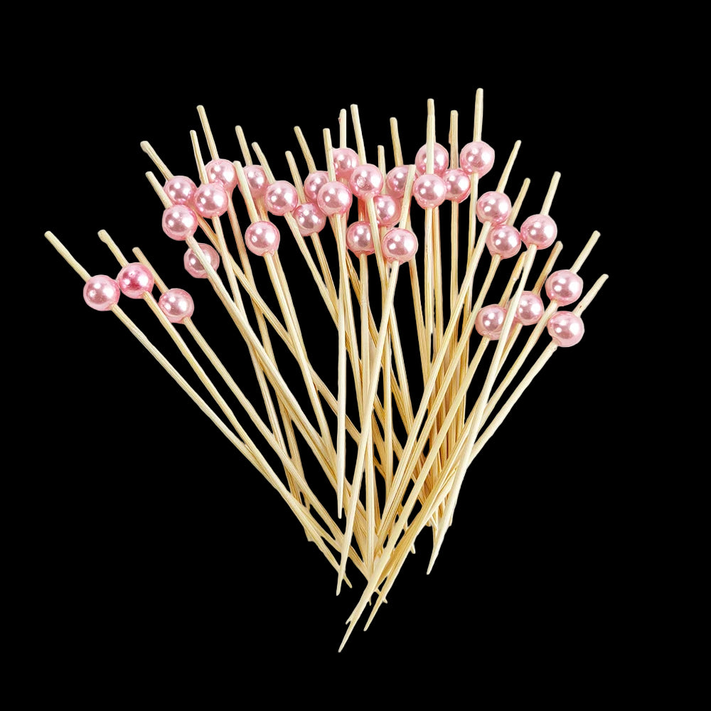 Wooden skewers with pink beads on a white plate