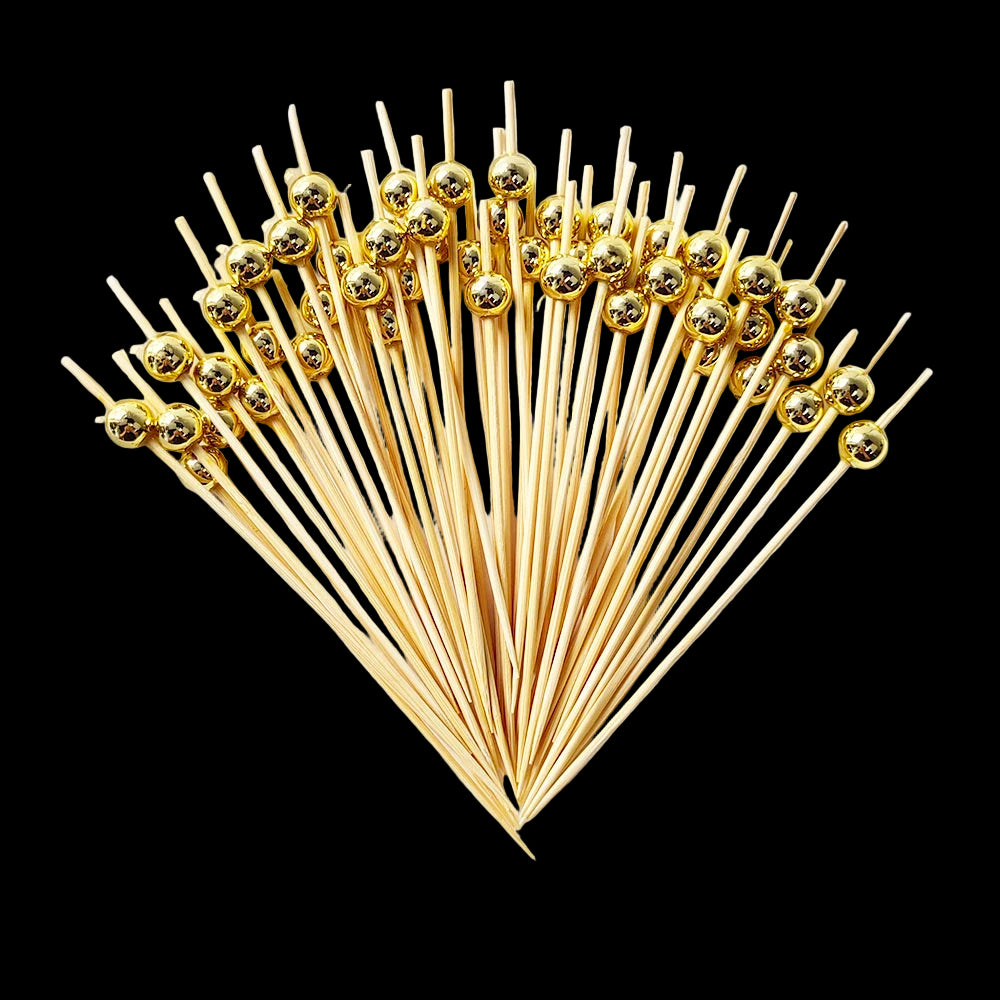 Set of gold toothpicks on a white plate