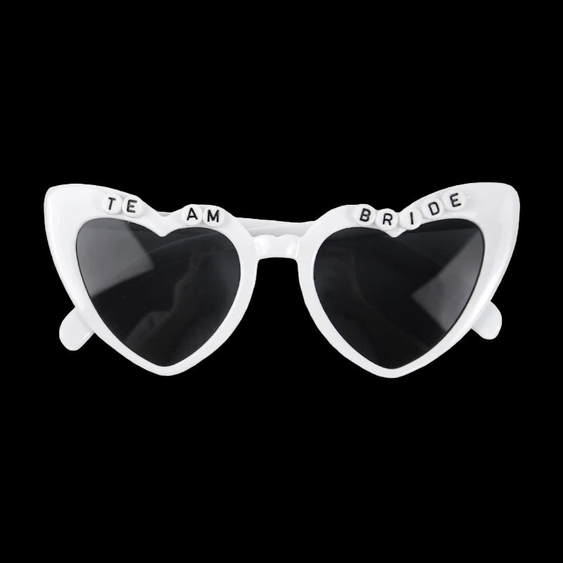 Sunglasses with heart-shaped lenses and 'Team Bride' text on a white background