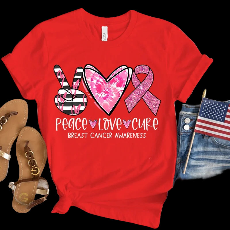 Red t-shirt with breast cancer awareness design featuring a heart, peace sign, and pink ribbon on a wooden surface.