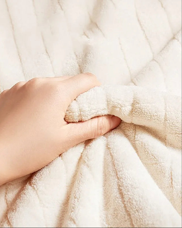 Hand touching a soft, beige fabric with Aibedila logo in the corner.