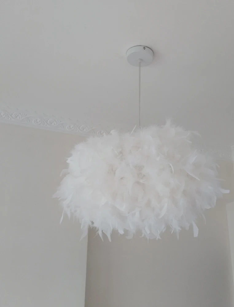 Feathered pendant light hanging from a ceiling in a room with neutral walls.