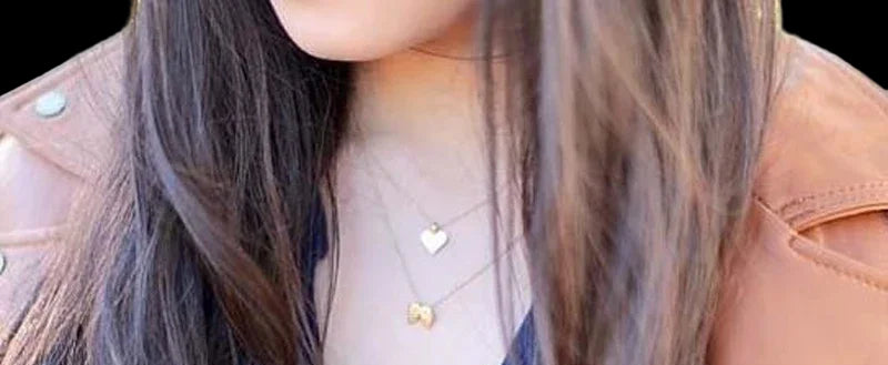 Person wearing a blue top and brown leather jacket with visible necklaces.