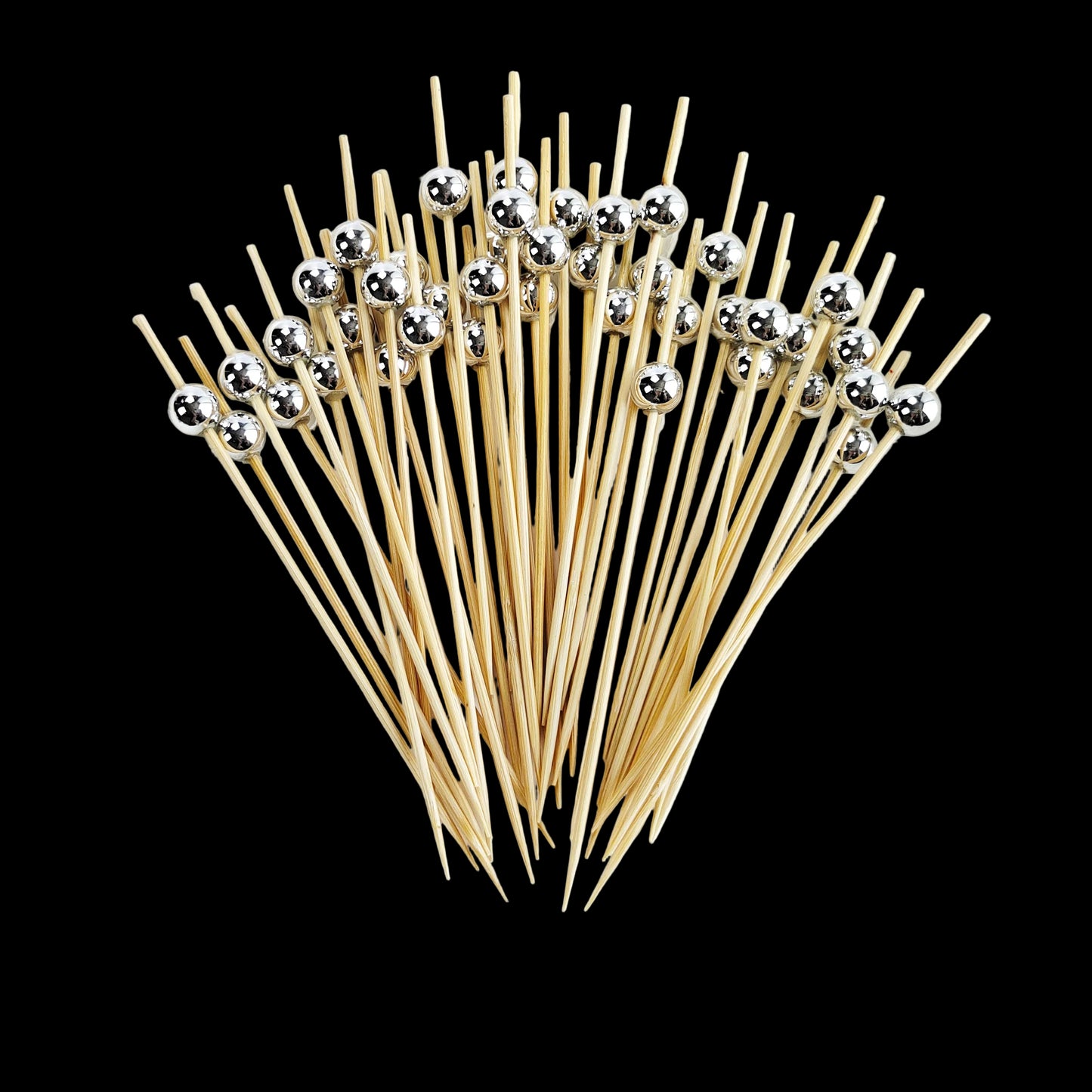 Wooden skewers with silver beads on a white plate