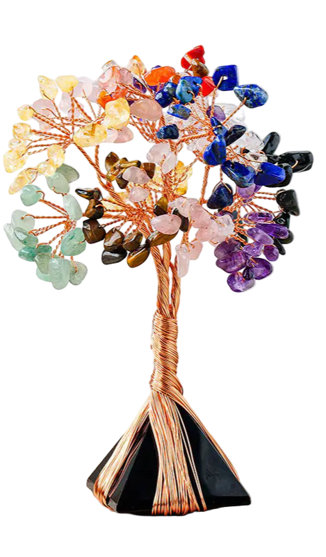 Multicolored crystal tree on a wooden surface with a candle and books in the background.