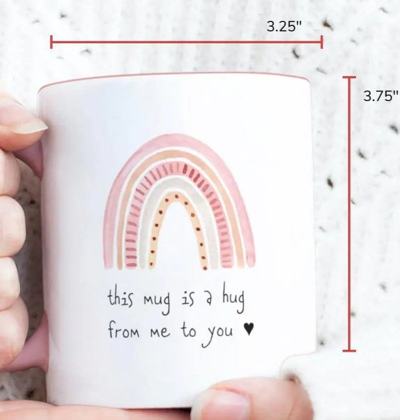 White mug with rainbow design and text held by a person, with capacity label and dimensions shown.