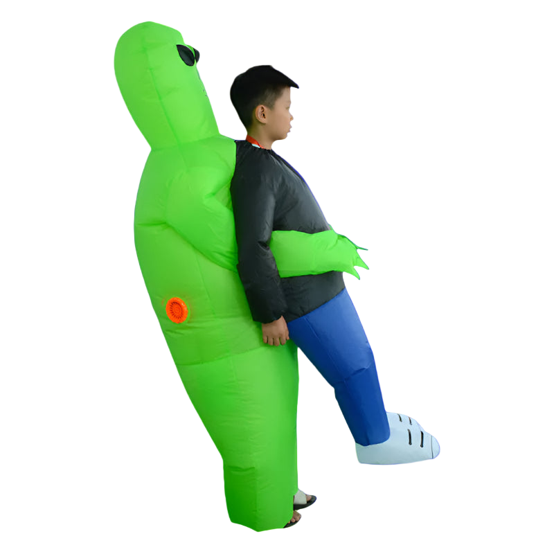 Child wearing a green inflatable dinosaur costume against a white brick wall.