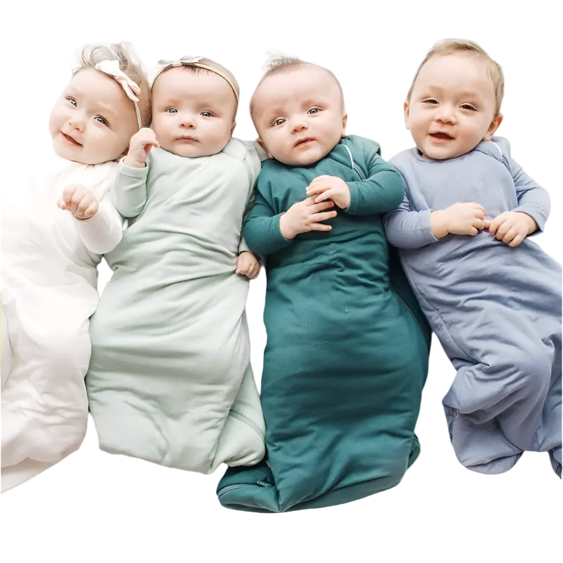 Four babies wrapped in colorful swaddles lying on a white surface
