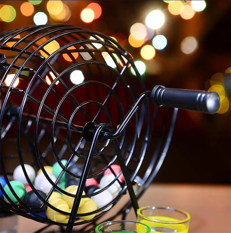 Black metal carnival-style prize wheel with colorful balls and glasses on a blurred lights background