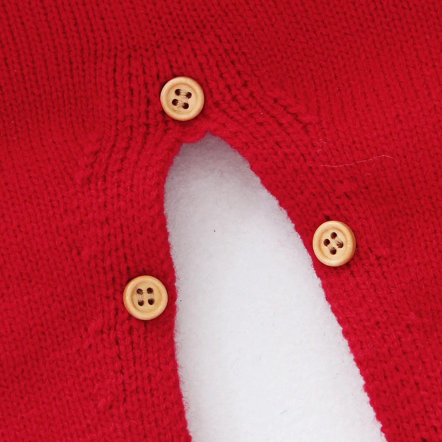 Close-up of a red garment with three buttons on a white background