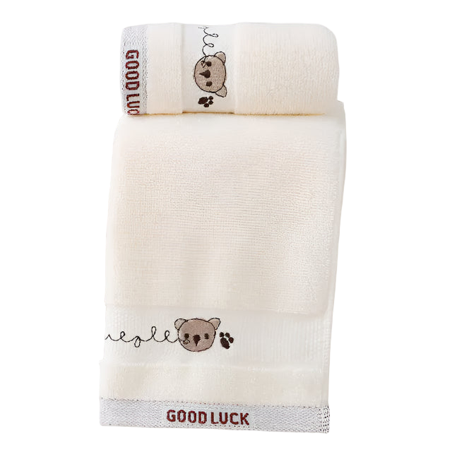 Two cream-colored towels with embroidered bear designs and 'Good Luck' text on a white background.